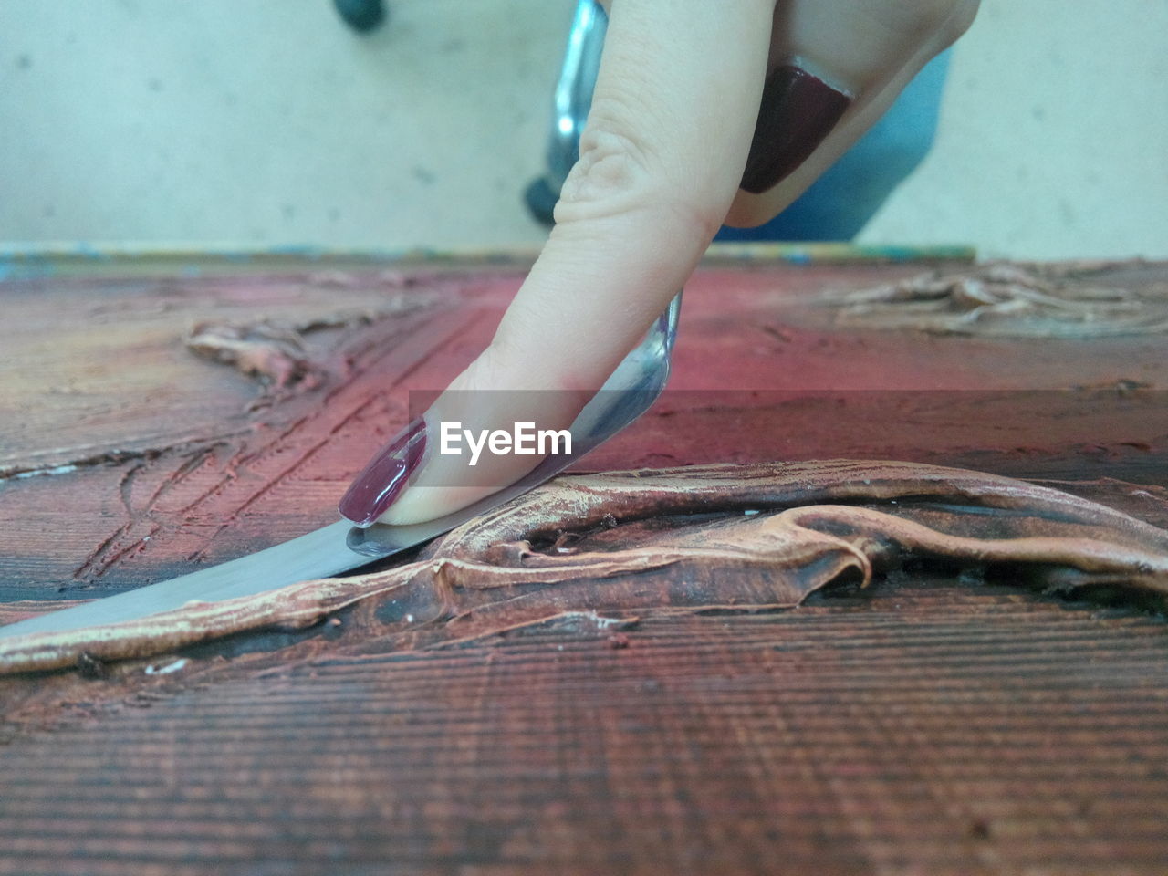 Cropped hand of woman holding tool on wooden table