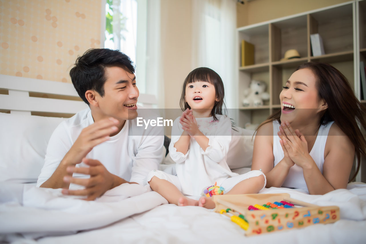 Family playing with toys on bed at home