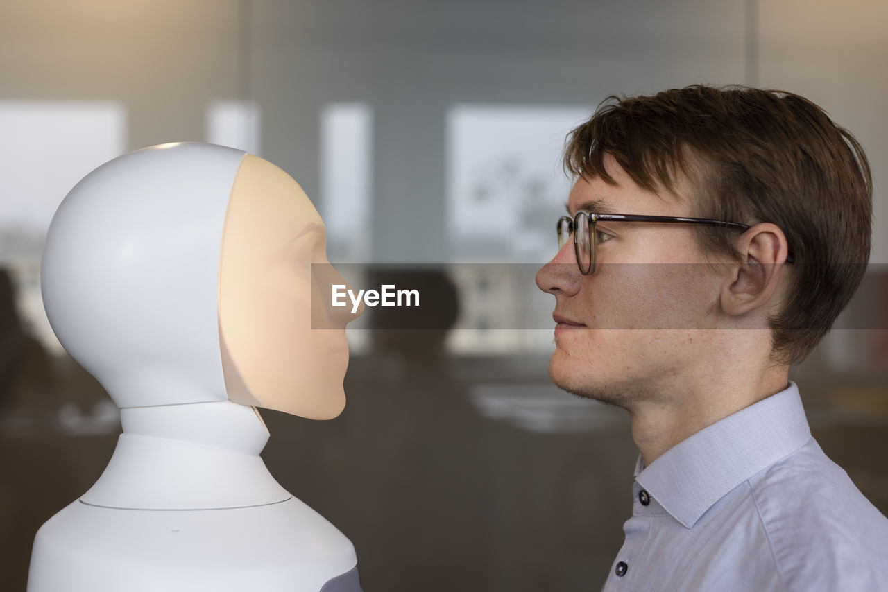 Young man looking at robot voice assistant