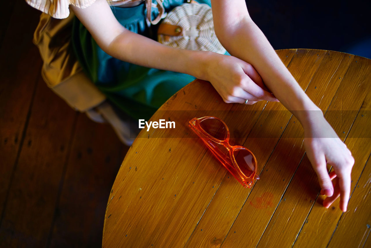 High angle view of woman sitting by wooden table