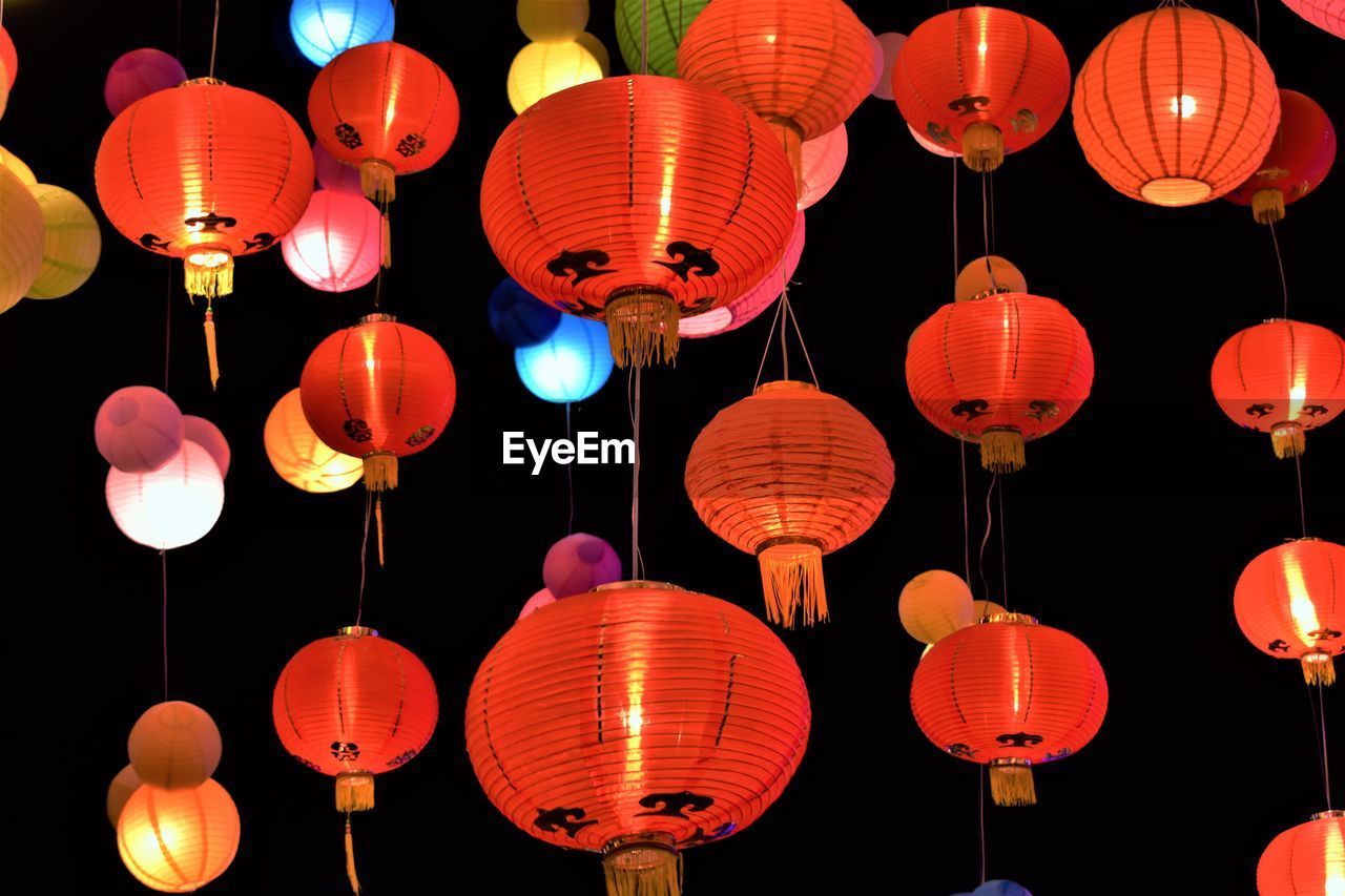 LOW ANGLE VIEW OF ILLUMINATED LANTERNS HANGING IN NIGHT