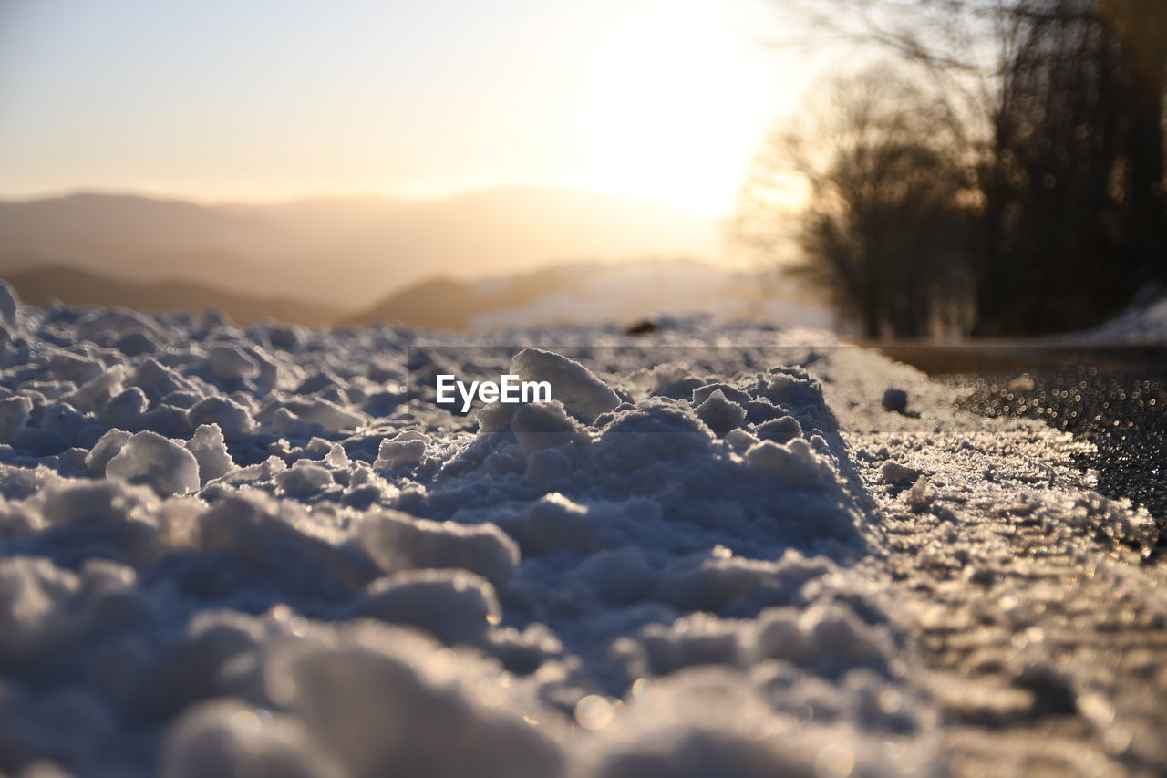 CLOSE-UP OF SNOW ON LAND AGAINST SKY