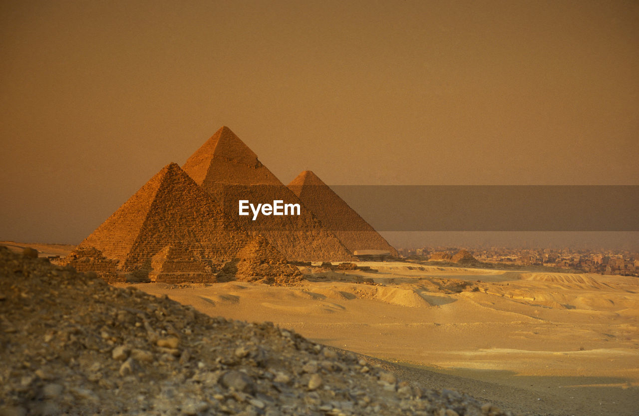 Ancient stone pyramids on desert landscape against sky