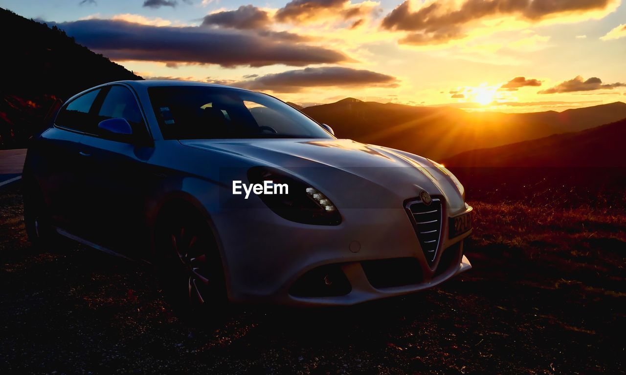 VIEW OF CAR ON LANDSCAPE AGAINST SUNSET