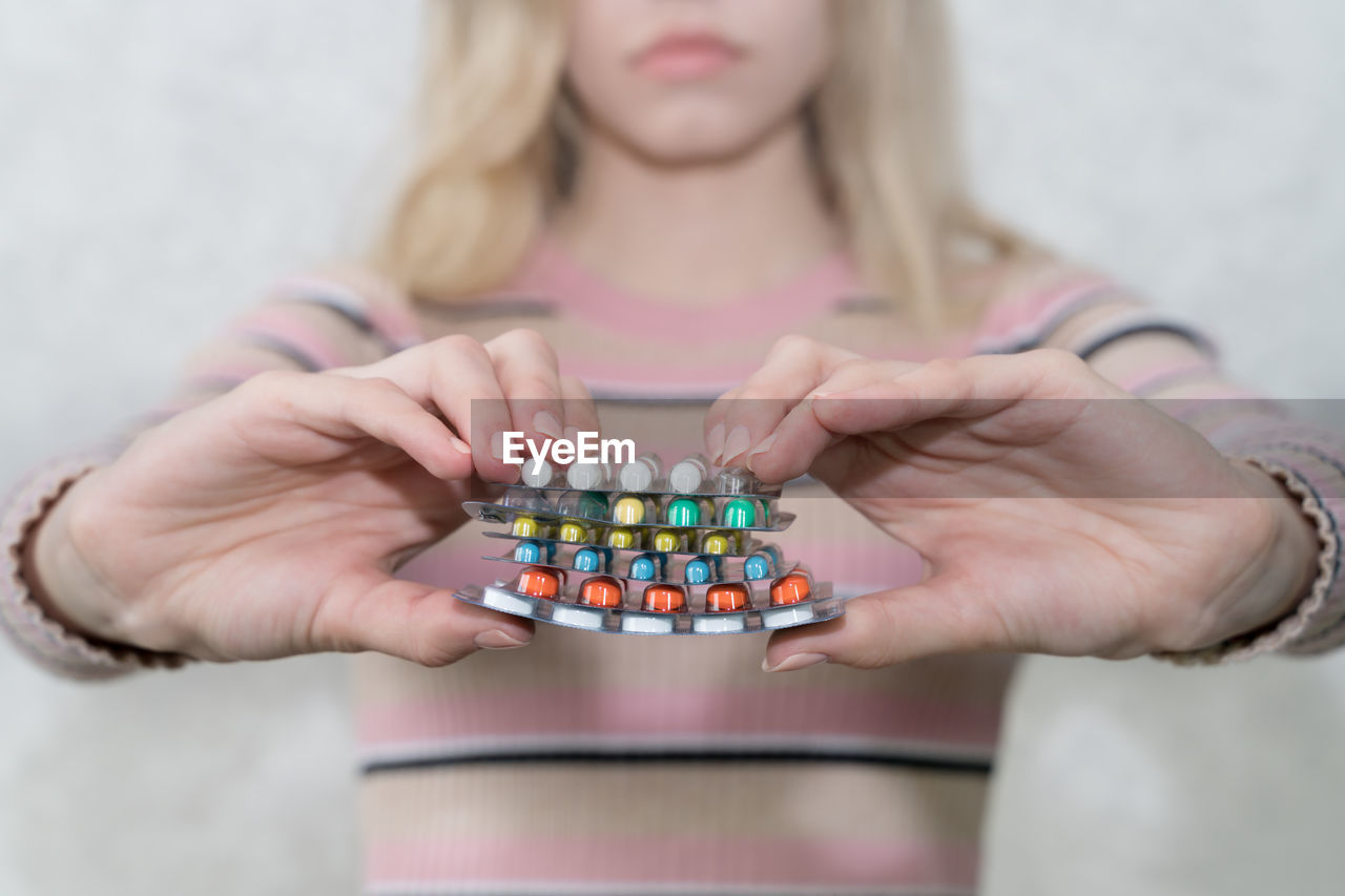 Girl holds a lot of blisters with pills closeup