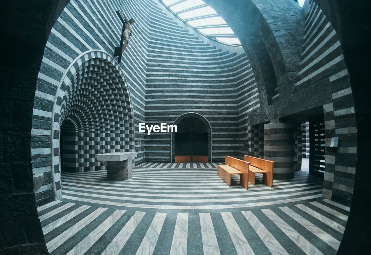 REAR VIEW OF WOMAN SITTING ON BENCH OUTSIDE BUILDING
