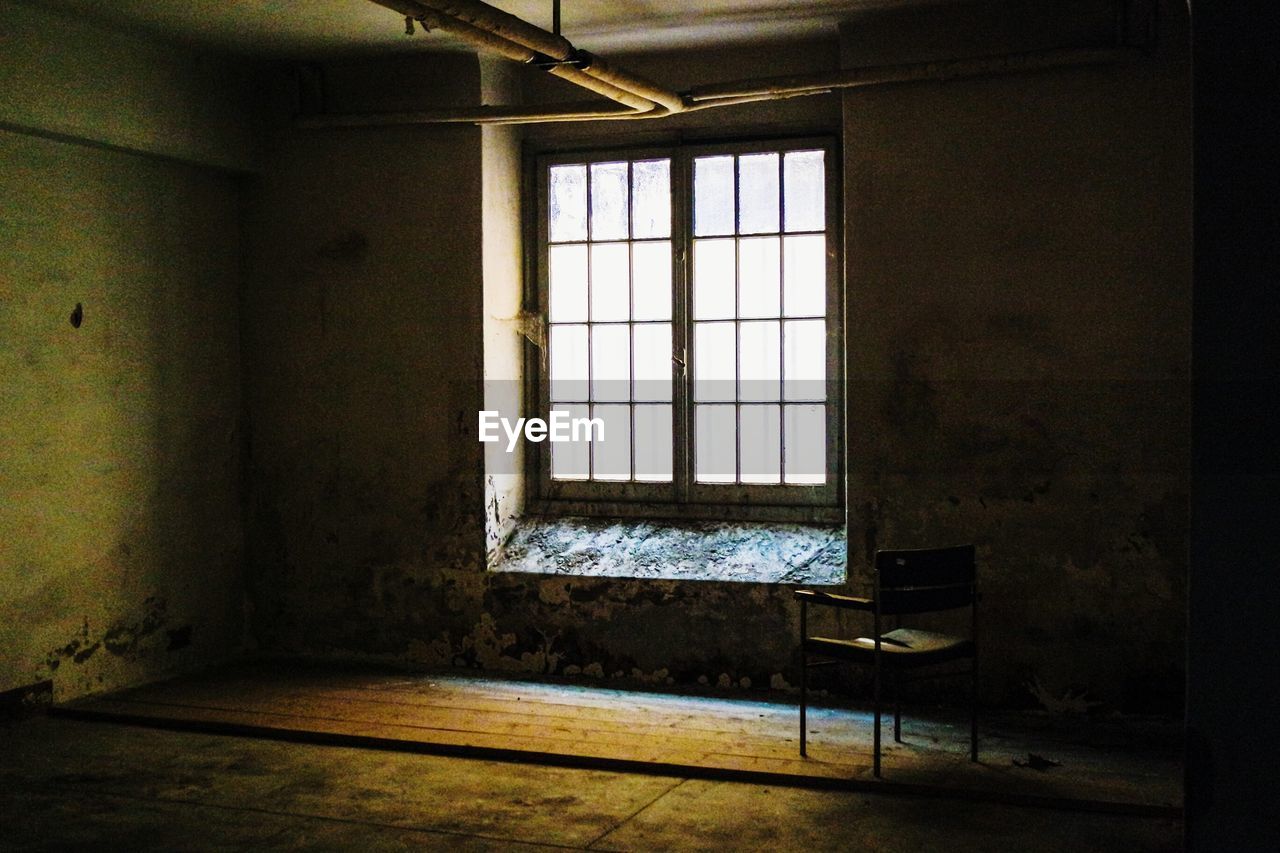 Interior of empty chair by window in abandoned home