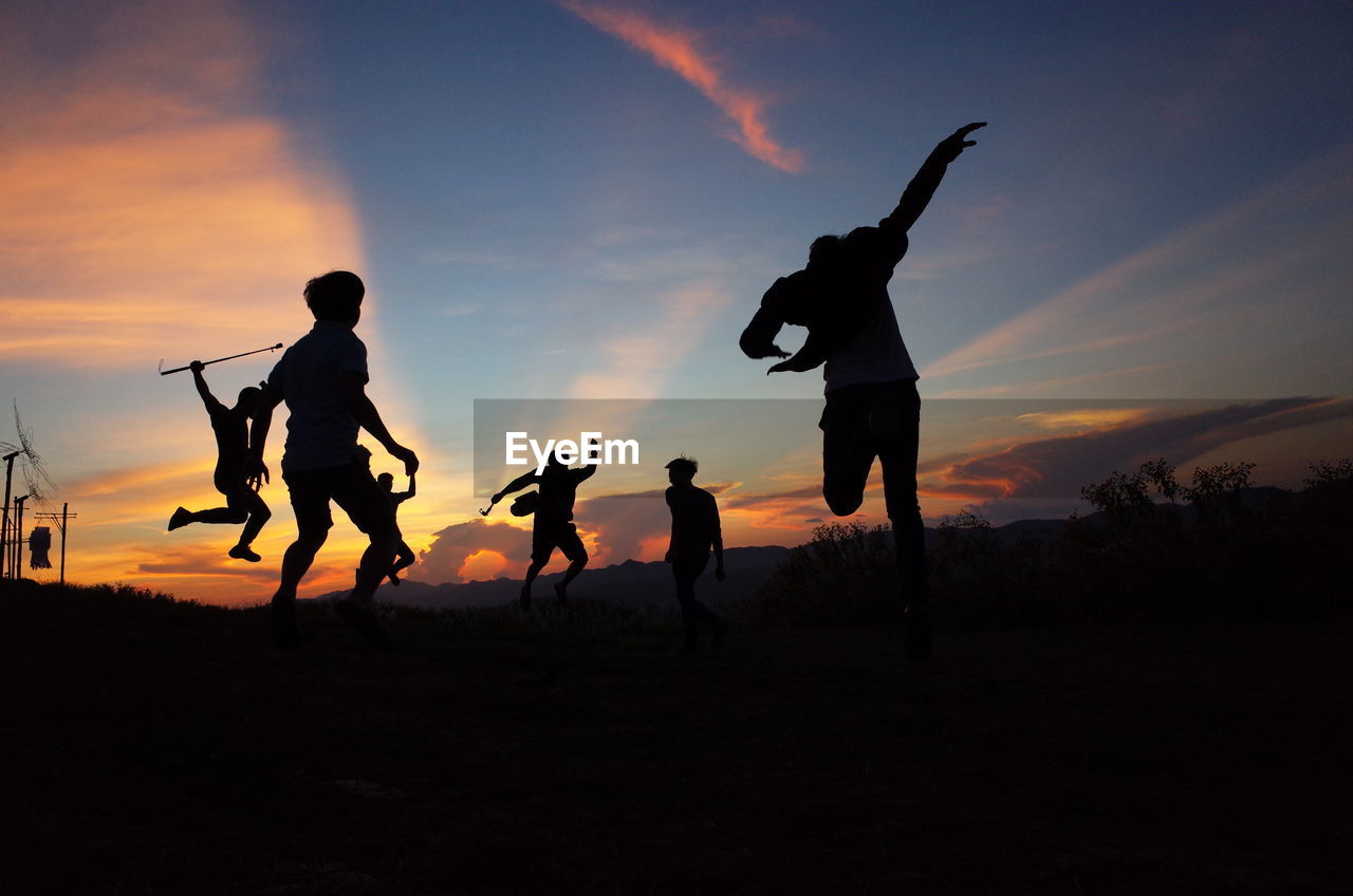 Silhouette men standing against sky during sunset