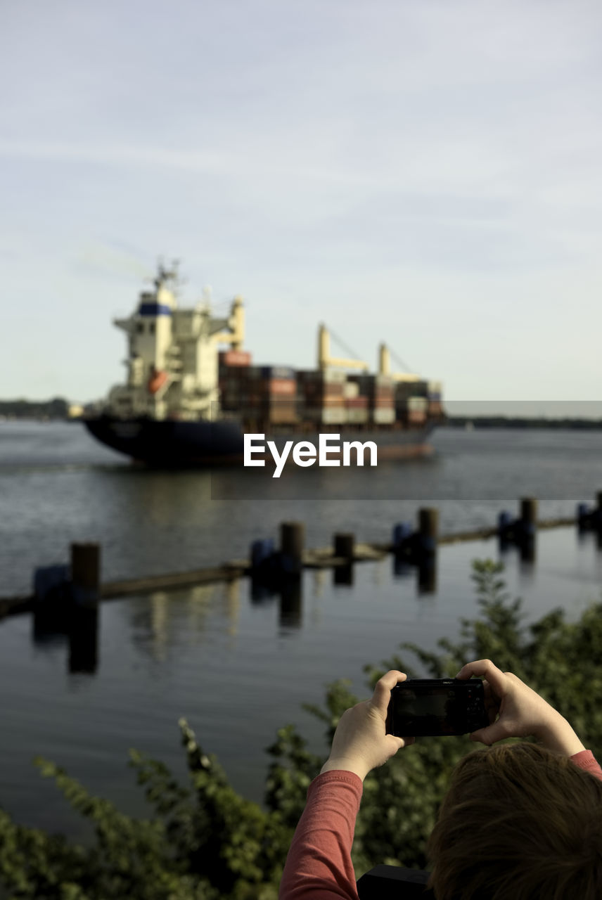 Kid photographing a container ship