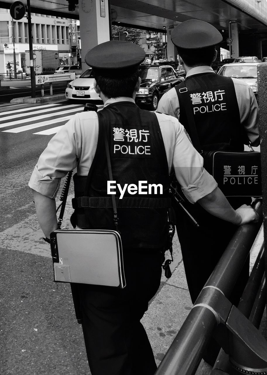 Rear view of policemen standing on street