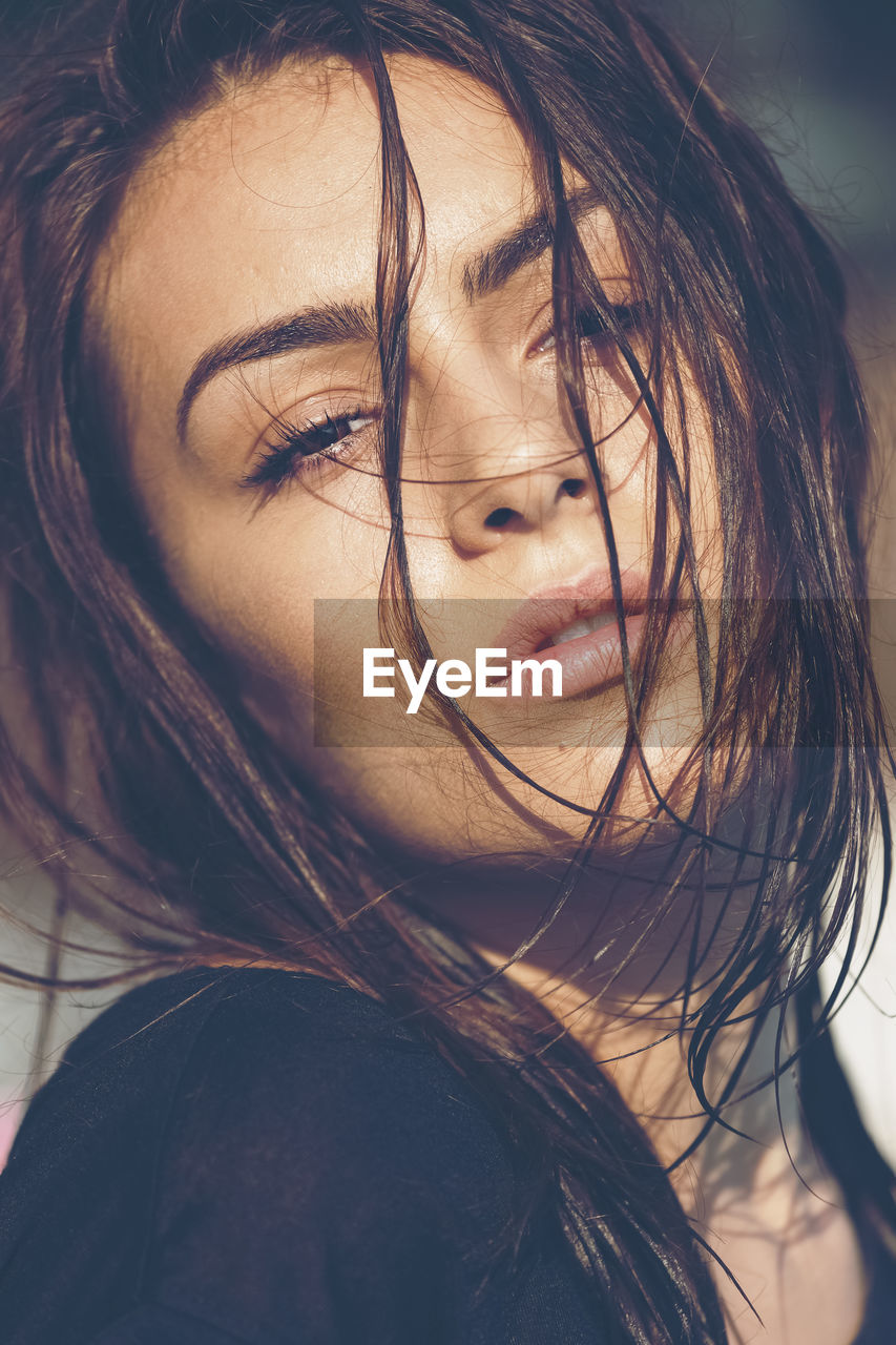 Portrait of carefree young woman with wet hair enjoying sun