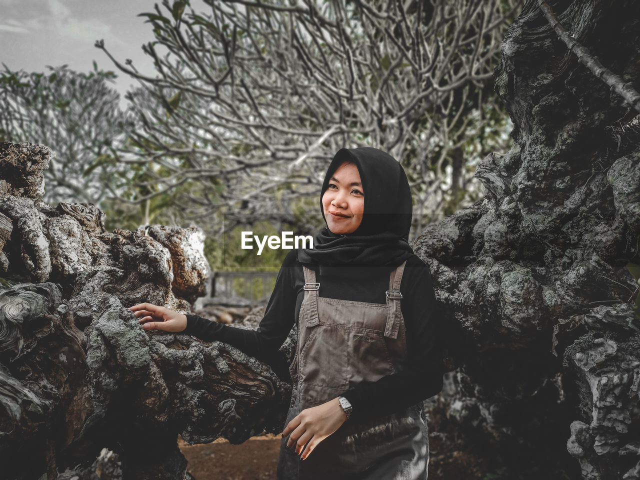 Young woman standing on rock against trees