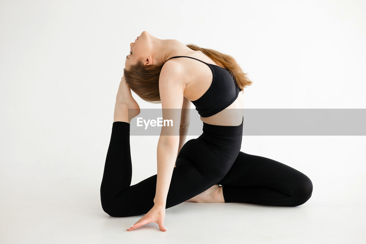 Beautiful sports girl doing stretching on a white background