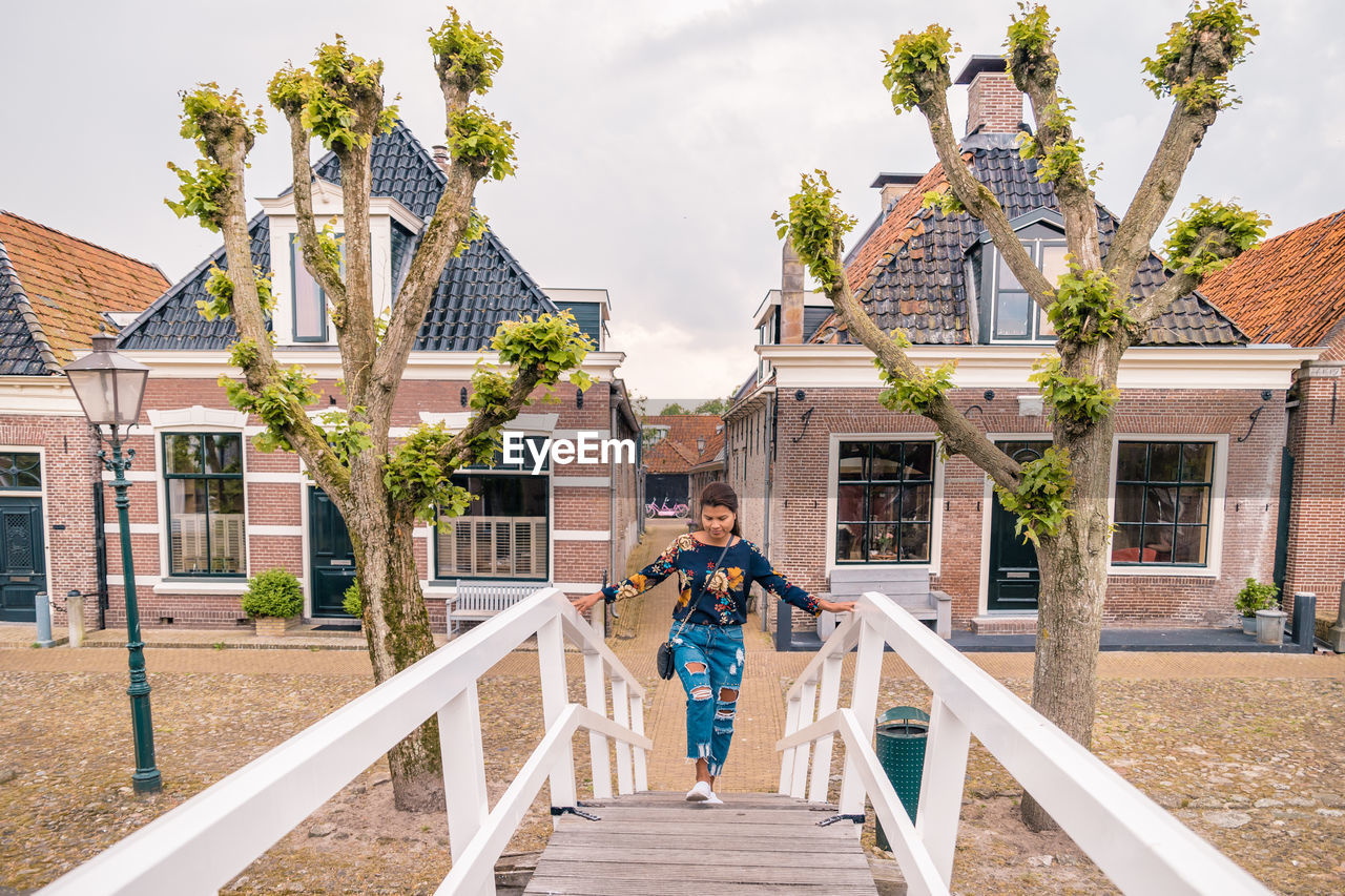 High angle view of mid adult woman moving up on steps against buildings in town