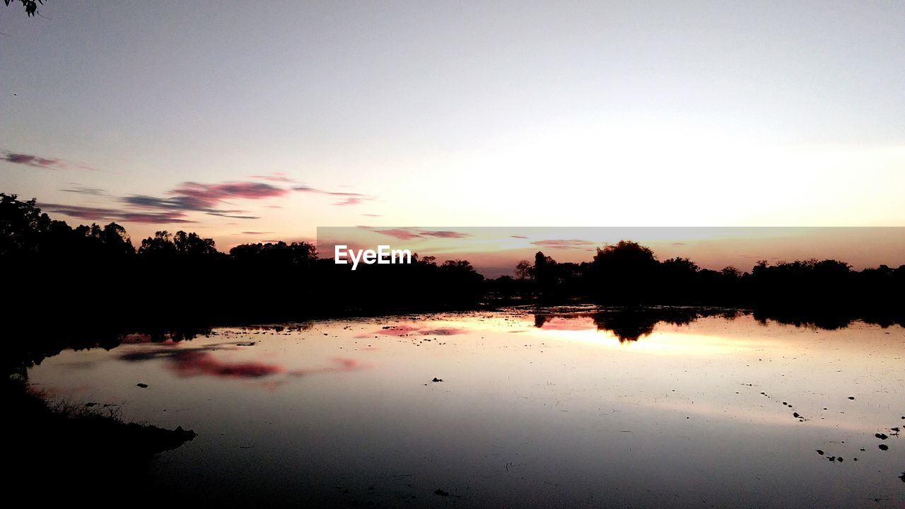 SCENIC VIEW OF LAKE AGAINST SKY AT SUNSET