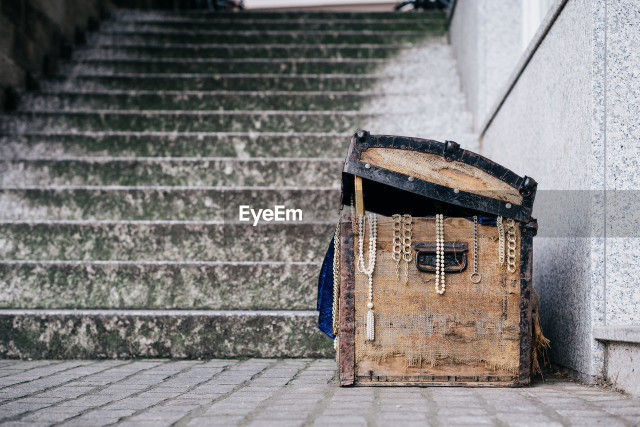 Old treasure box by staircase against wall