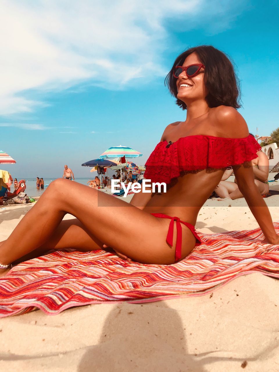 Young woman sitting on beach against sky