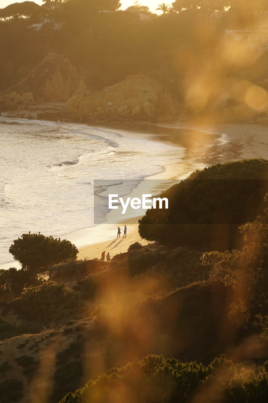 Scenic view of sea with people at the beach during sunset