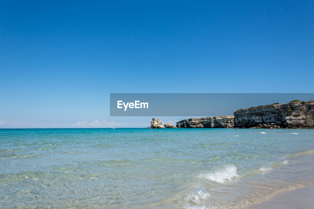 SEA AND BUILDINGS AGAINST CLEAR BLUE SKY