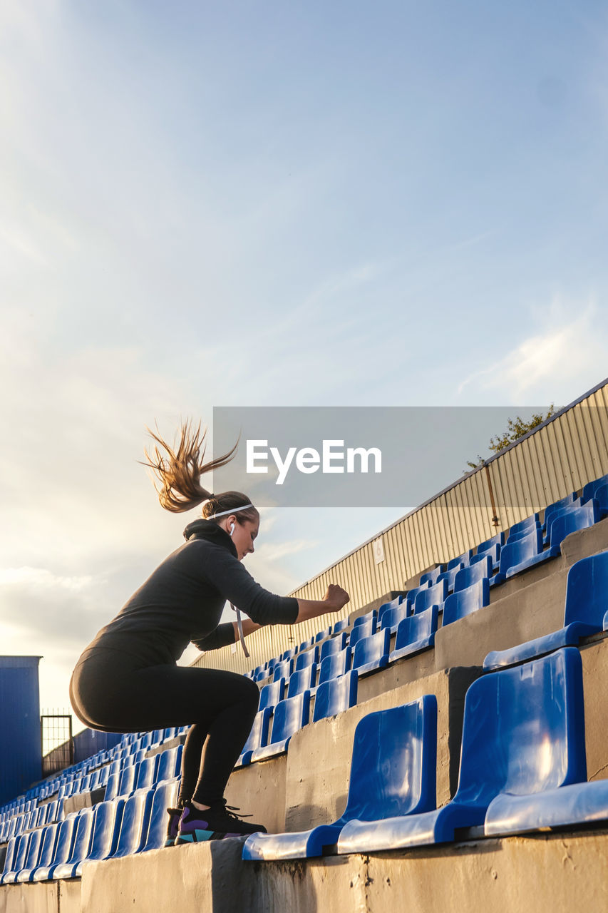 Full length of woman exercising in stadium