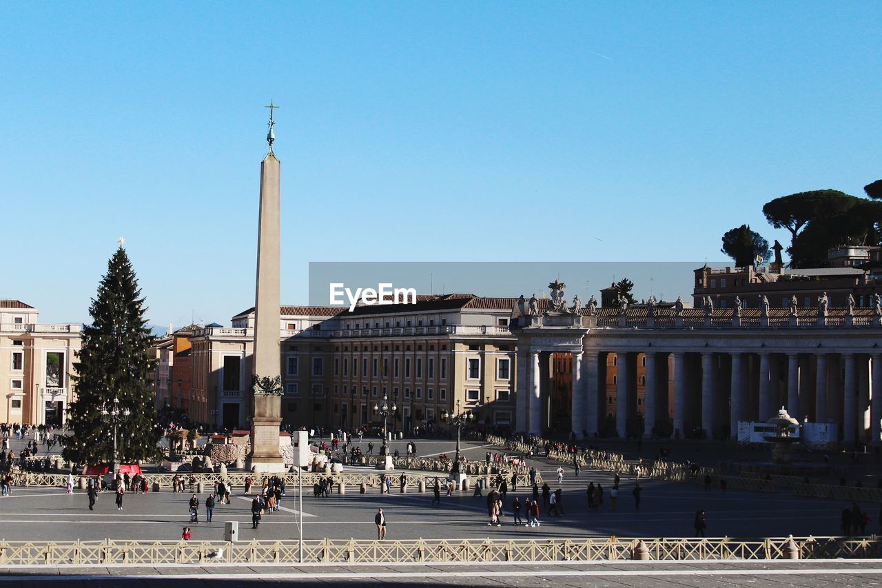 architecture, built structure, city, town square, building exterior, landmark, sky, travel destinations, cityscape, clear sky, plaza, travel, large group of people, crowd, downtown, group of people, nature, tourism, history, sunny, the past, day, building, street, blue, outdoors, skyline, urban area, government, town, monument, sunlight, place of worship, architectural column
