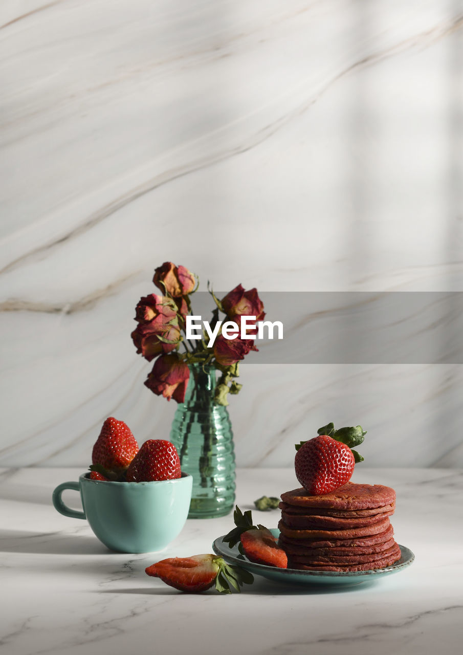 Still life with pink strawberry pancakes on a turquoise plate with sour cream