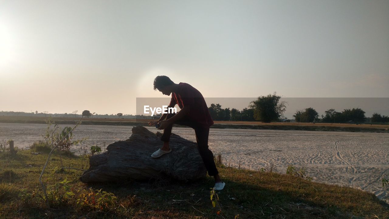 MAN STANDING ON FIELD AGAINST CLEAR SKY