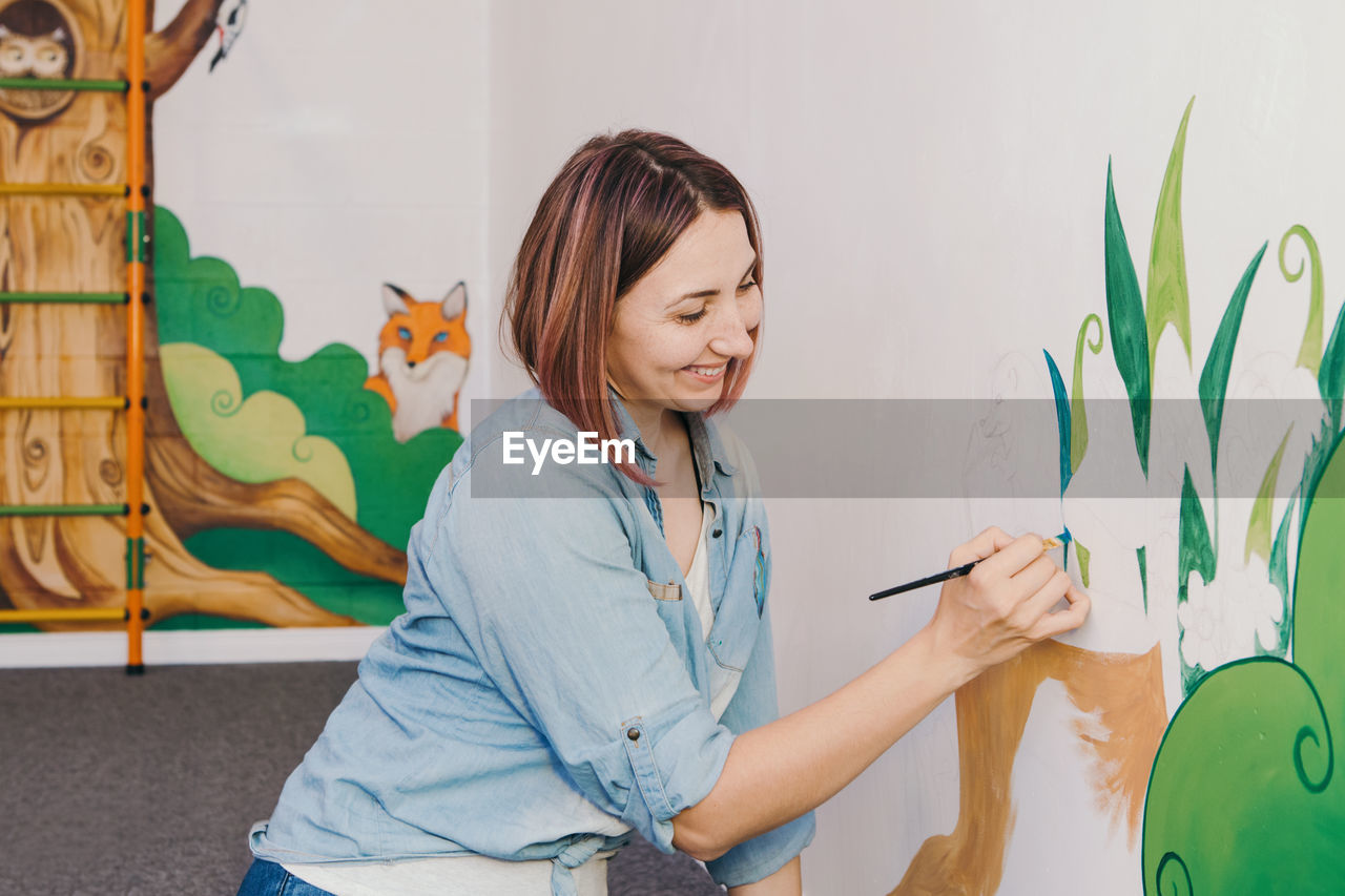 Woman painting wall at home