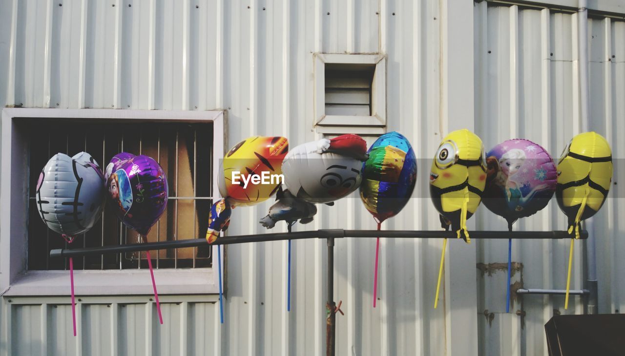 Colorful balloons hanging to pole against house