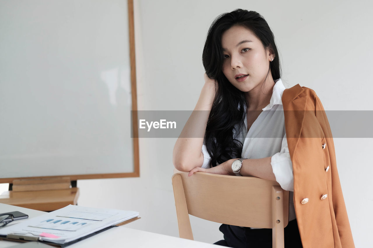 Young woman looking away while sitting on table