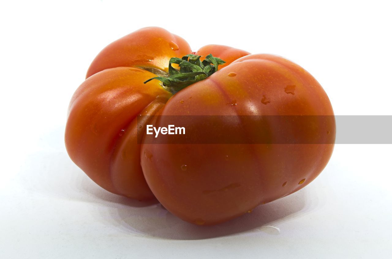 CLOSE-UP OF FRESH TOMATOES WITH ORANGE OVER WHITE BACKGROUND