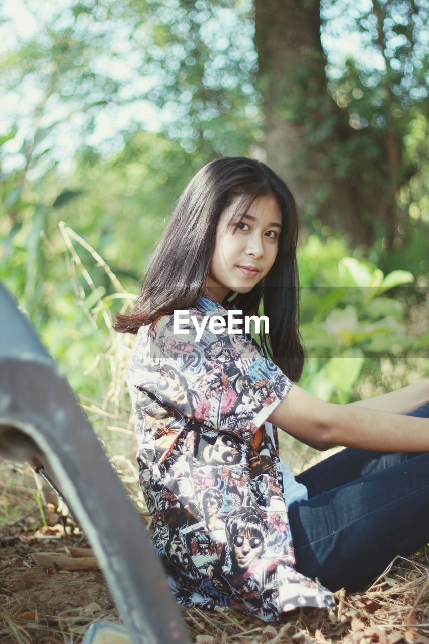 Side view portrait of young woman sitting on field