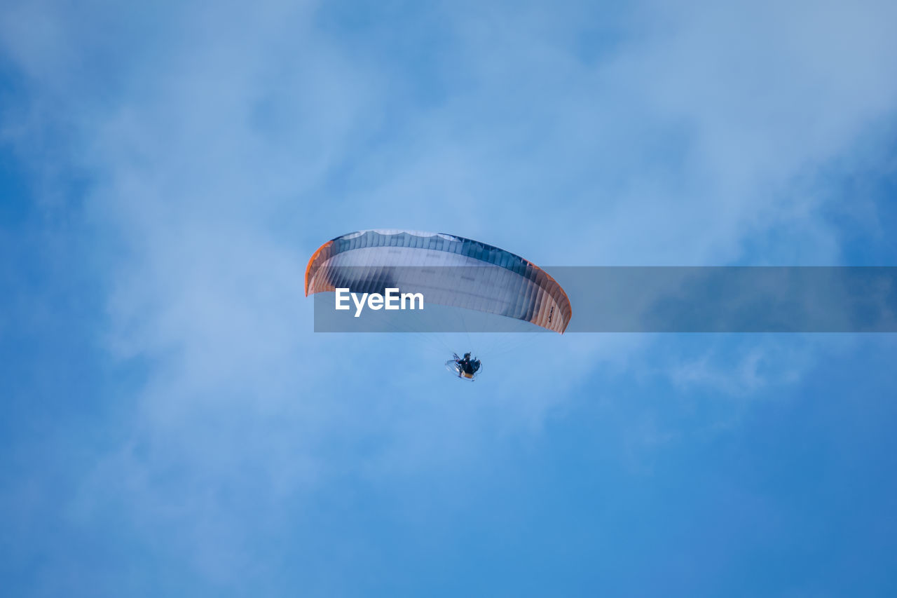 Low angle view of person paragliding against blue sky