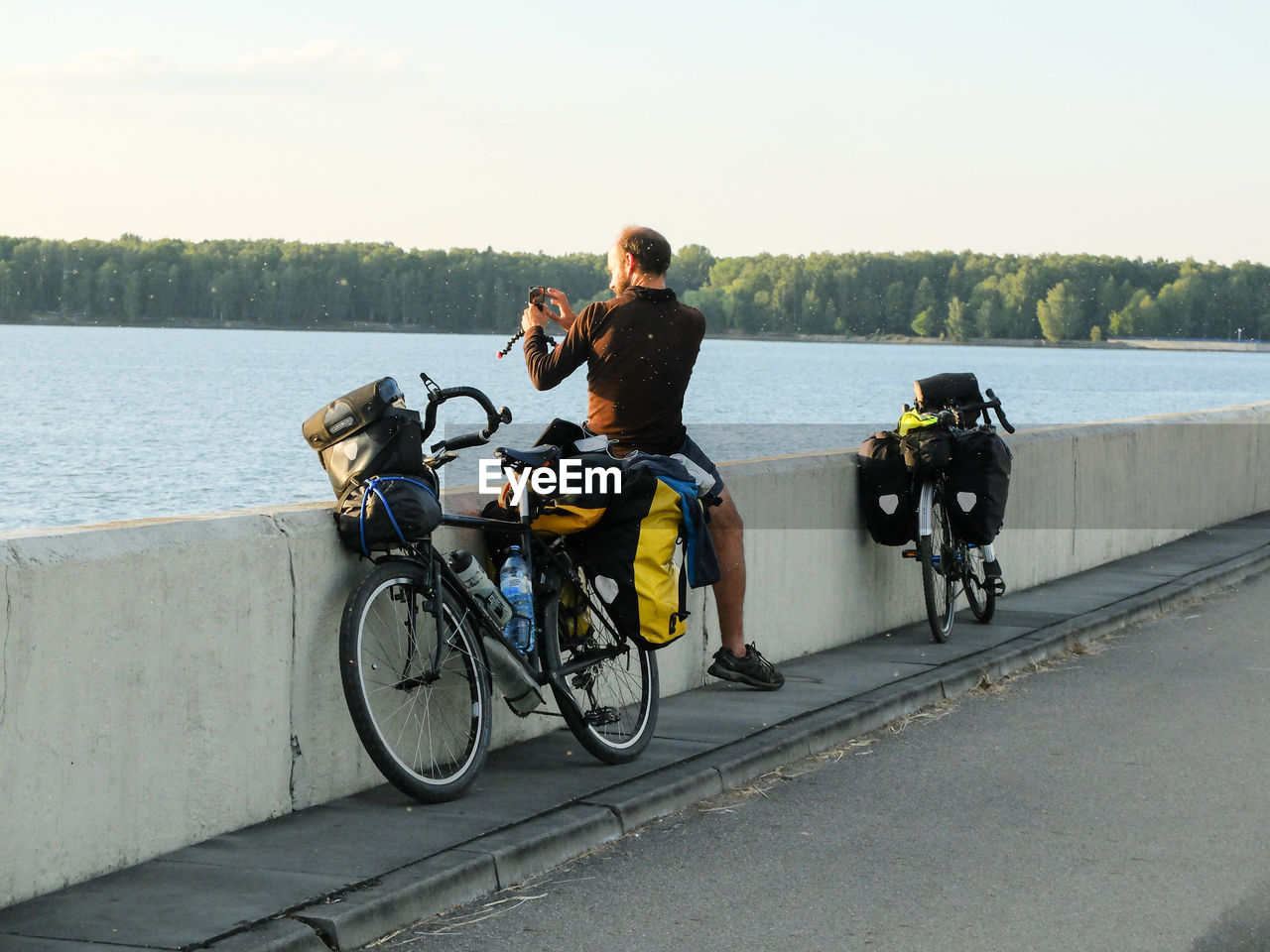 REAR VIEW OF BOY SITTING ON BICYCLE BY LAKE