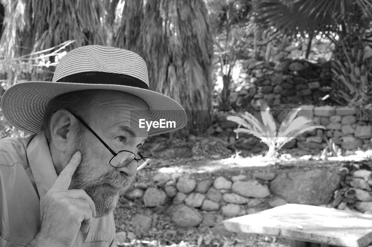 hat, one person, sun hat, plant, black and white, nature, day, fashion accessory, adult, clothing, leisure activity, lifestyles, tree, portrait, monochrome photography, person, headshot, outdoors, monochrome, men, women, land, growth, human face, casual clothing, sunlight, front view