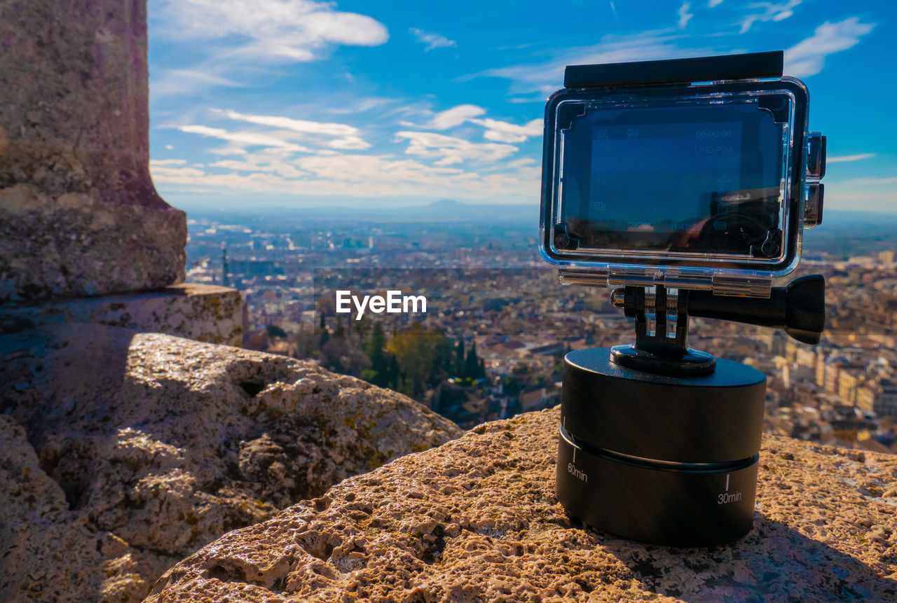 Close-up of camera on rock against sky
