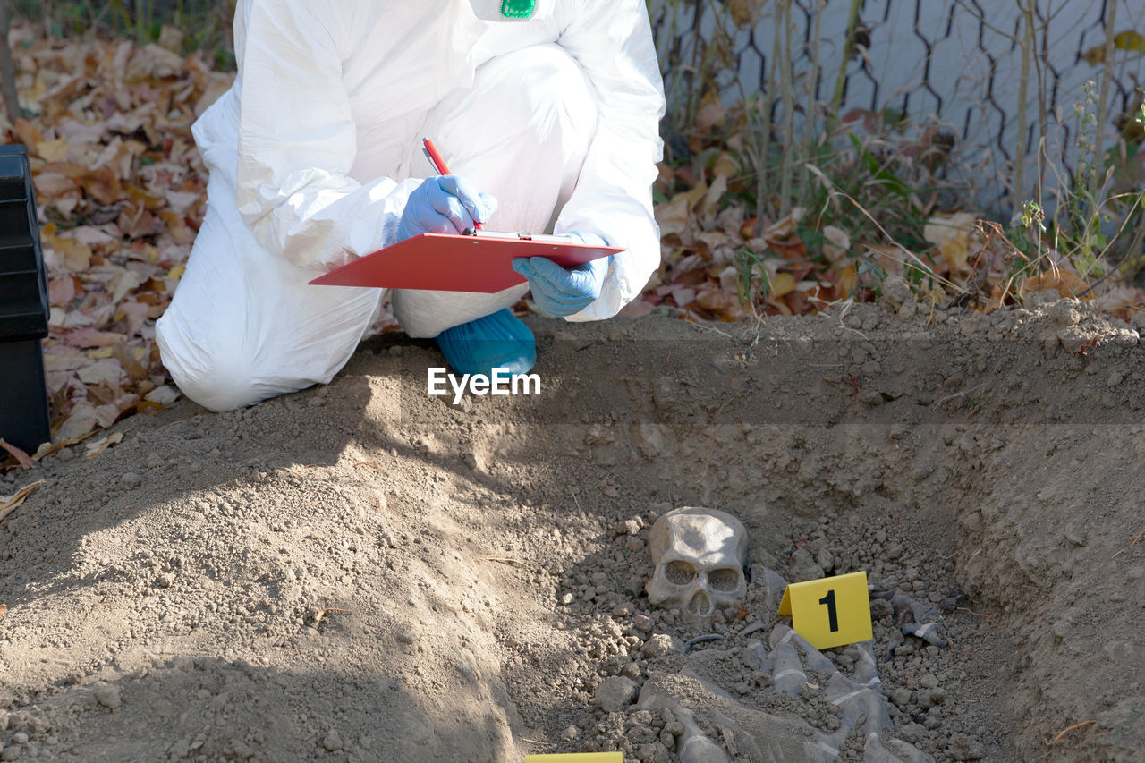 HIGH ANGLE VIEW OF MAN SITTING ON SAND IN BACK YARD