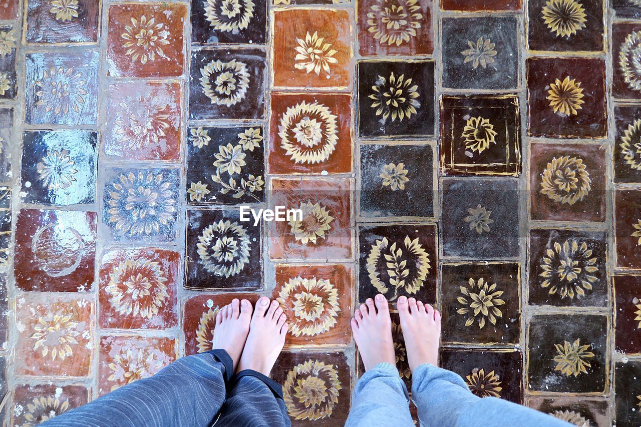 Low section of friends standing on patterned tiled floor