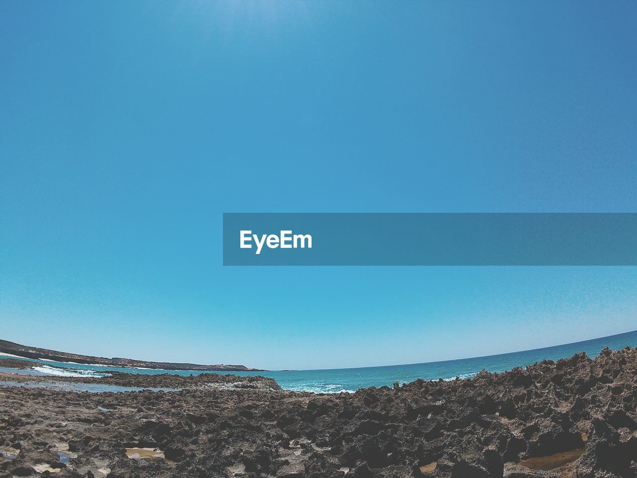 Scenic view of beach against clear blue sky