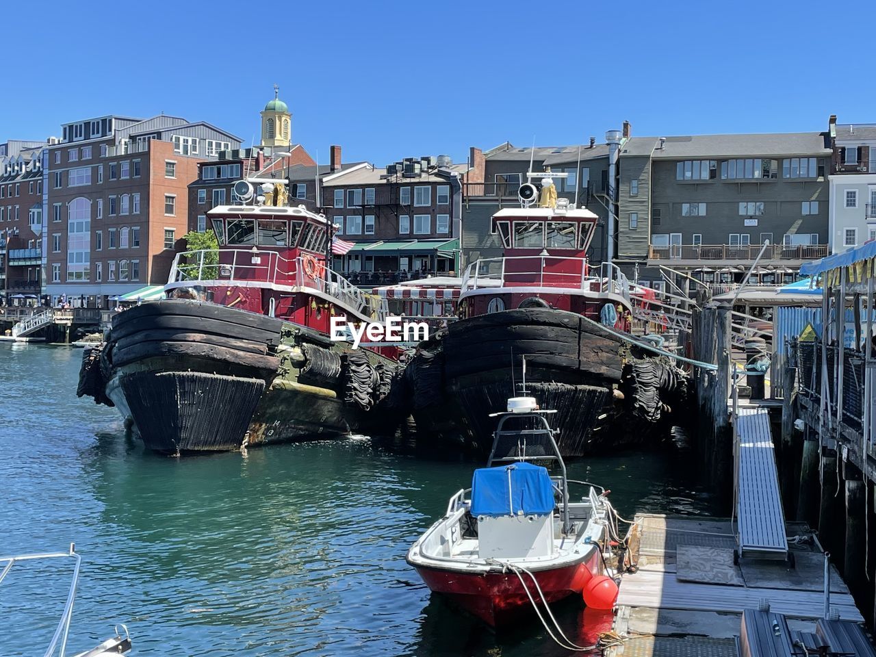 Boats moored at harbor against clear sky