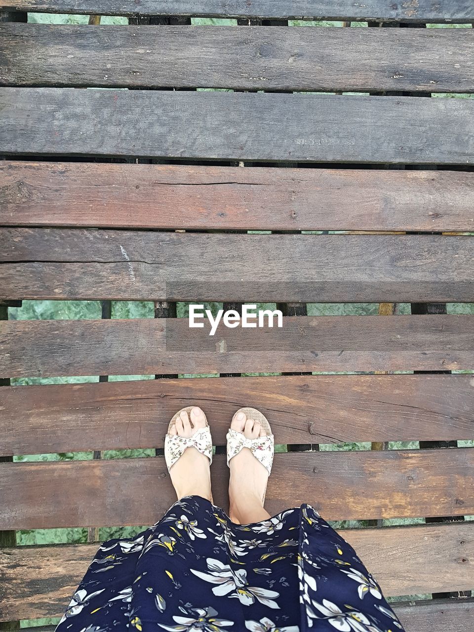 LOW SECTION OF WOMAN STANDING ON WOODEN FLOOR