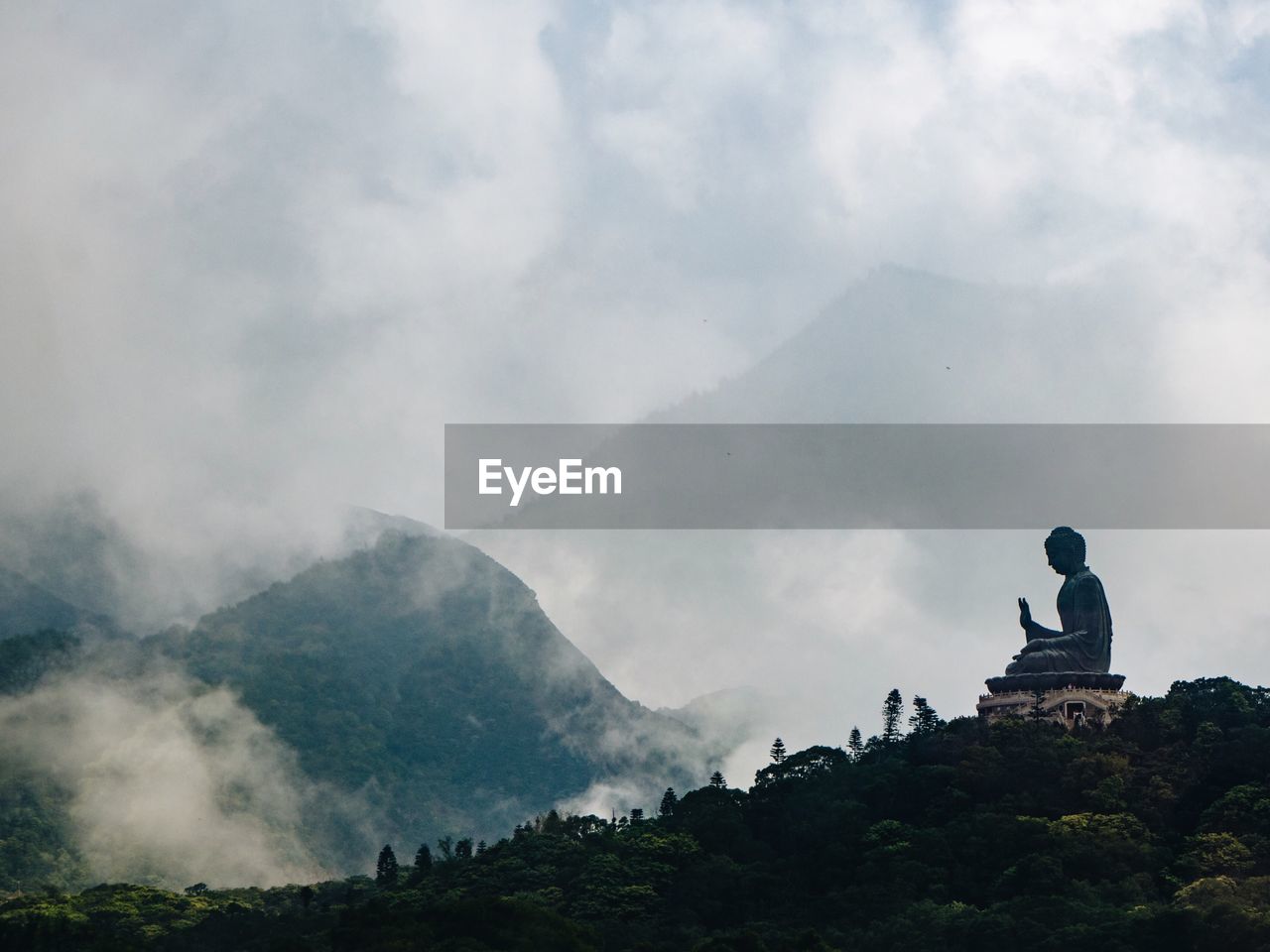 Buddha statue against mountains and cloudy sky