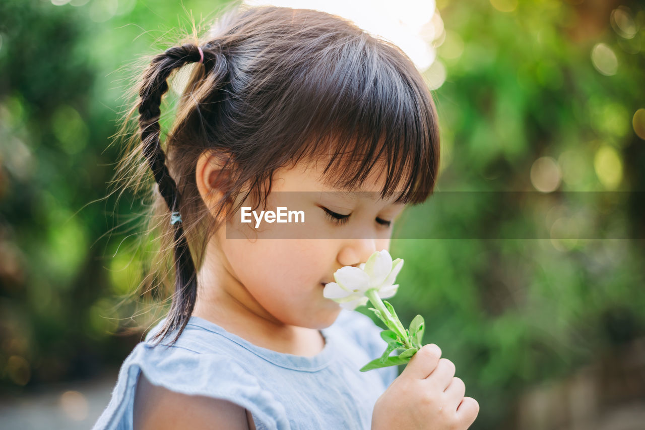 Close-up of cute girl holding flower outdoors