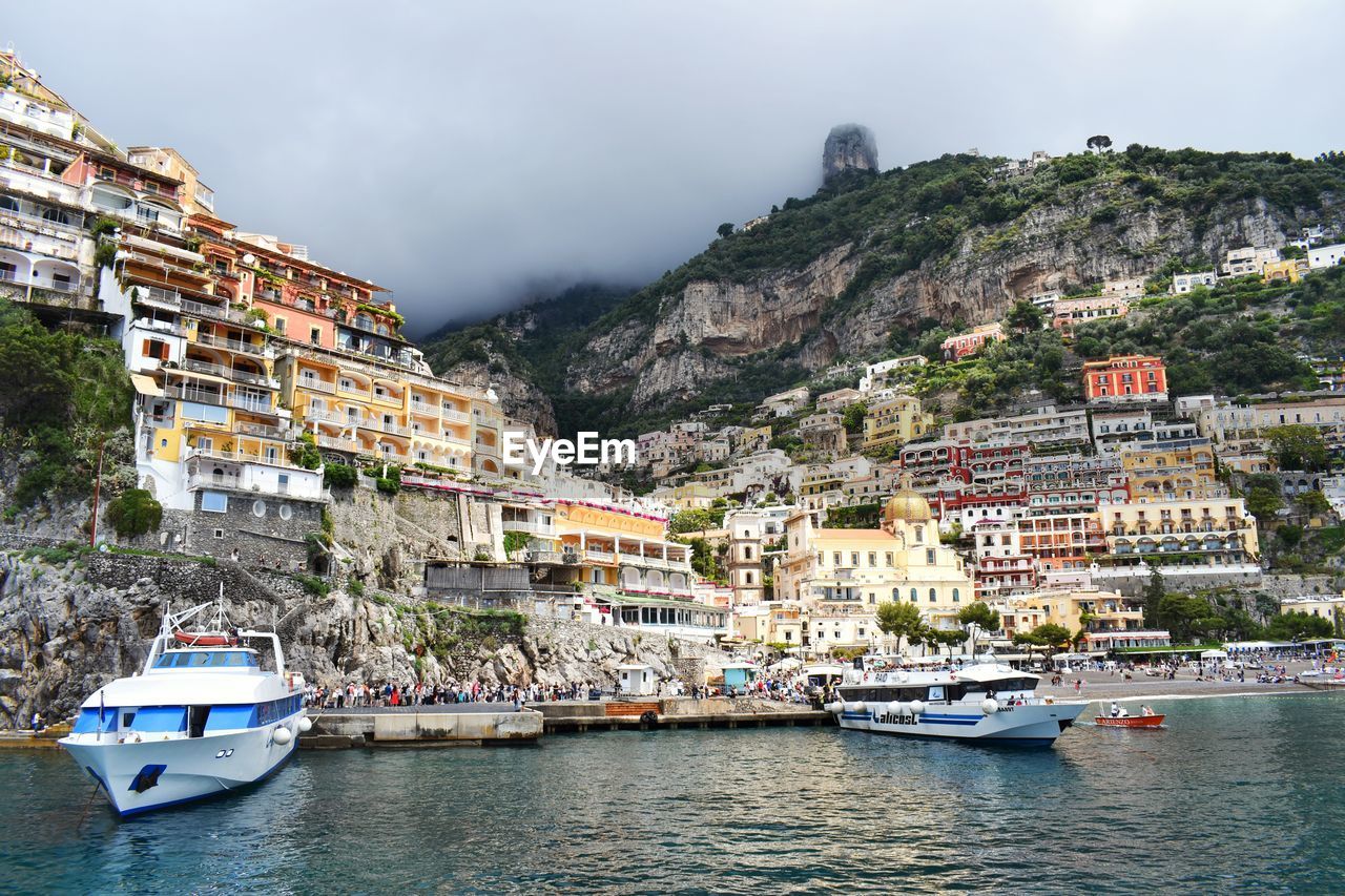 SAILBOATS MOORED IN SEA BY TOWN