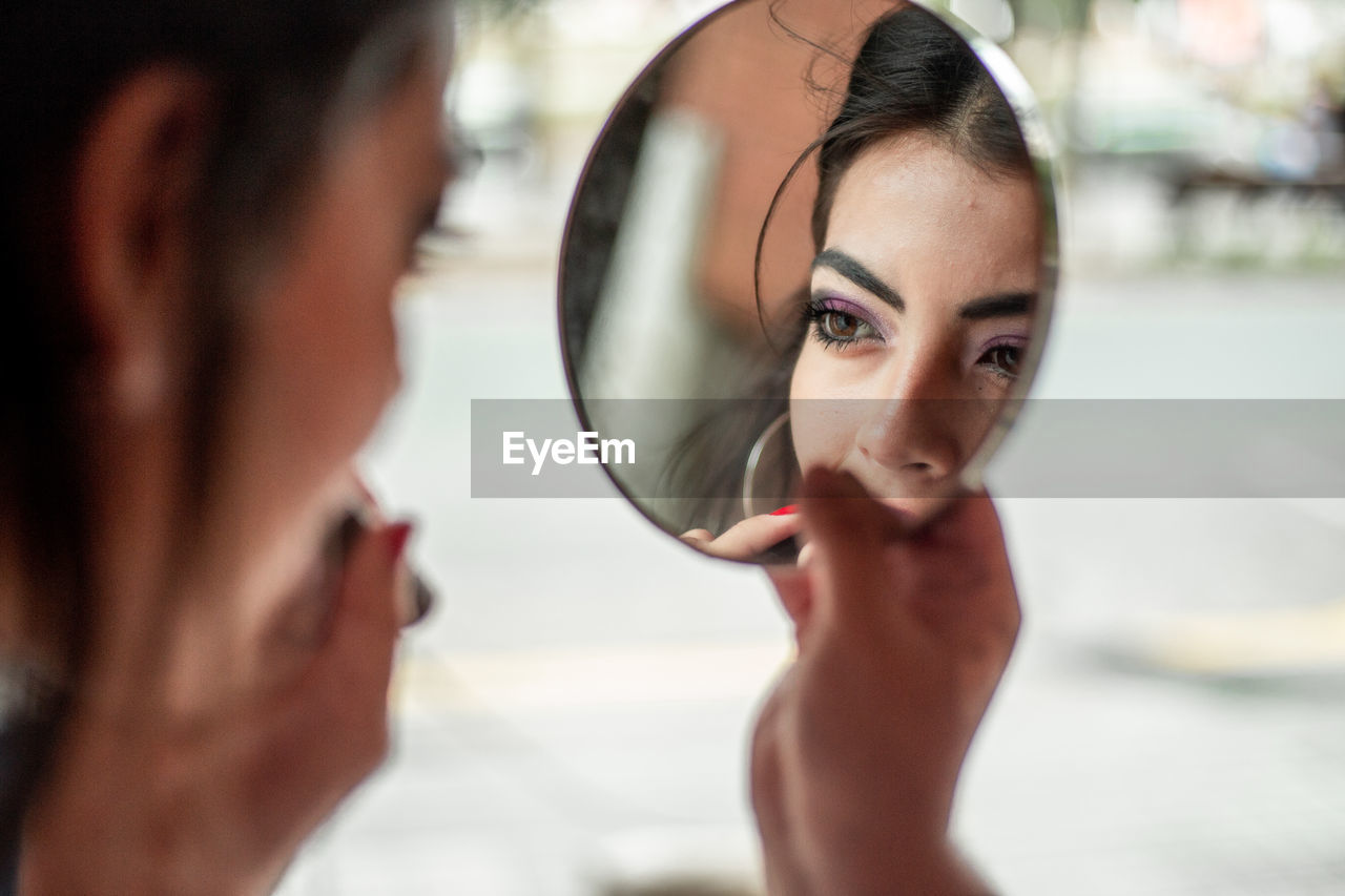 A beautiful woman doing her make up looking at a mirror