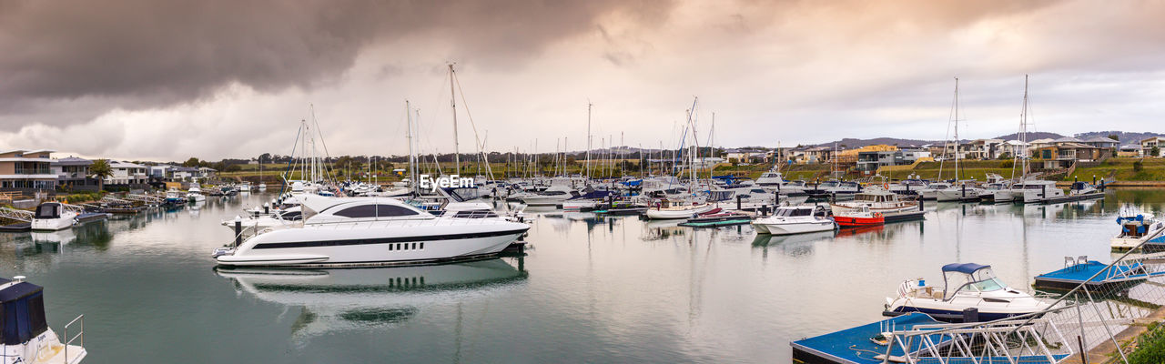 Sailboats moored at harbor against sky