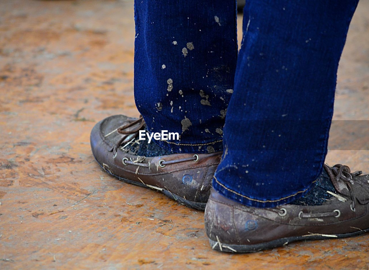 Low section of man wearing dirty shoes on wooden floor