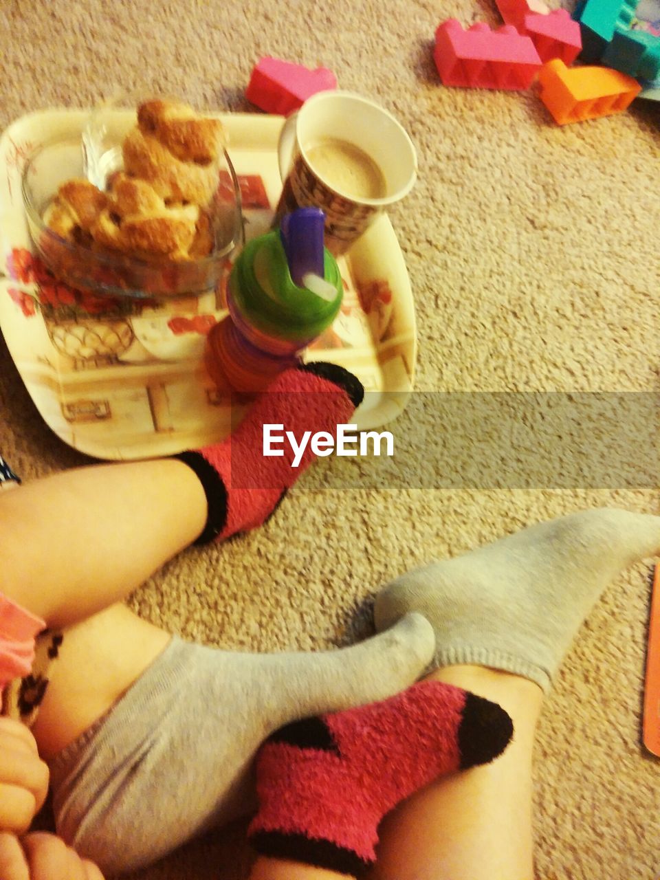 Low section of parent and child sitting by food on carpet