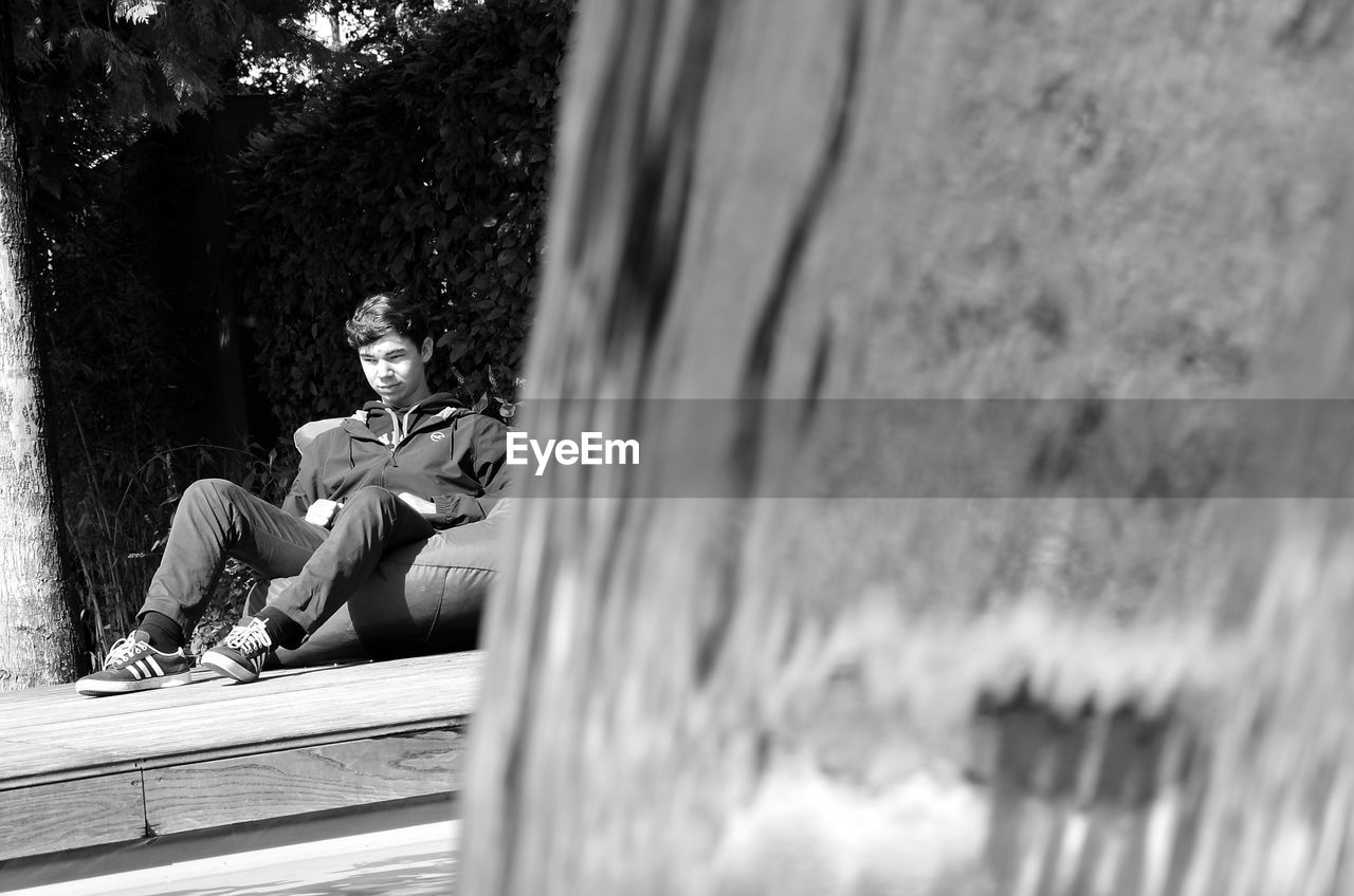 YOUNG MAN SITTING ON TREE