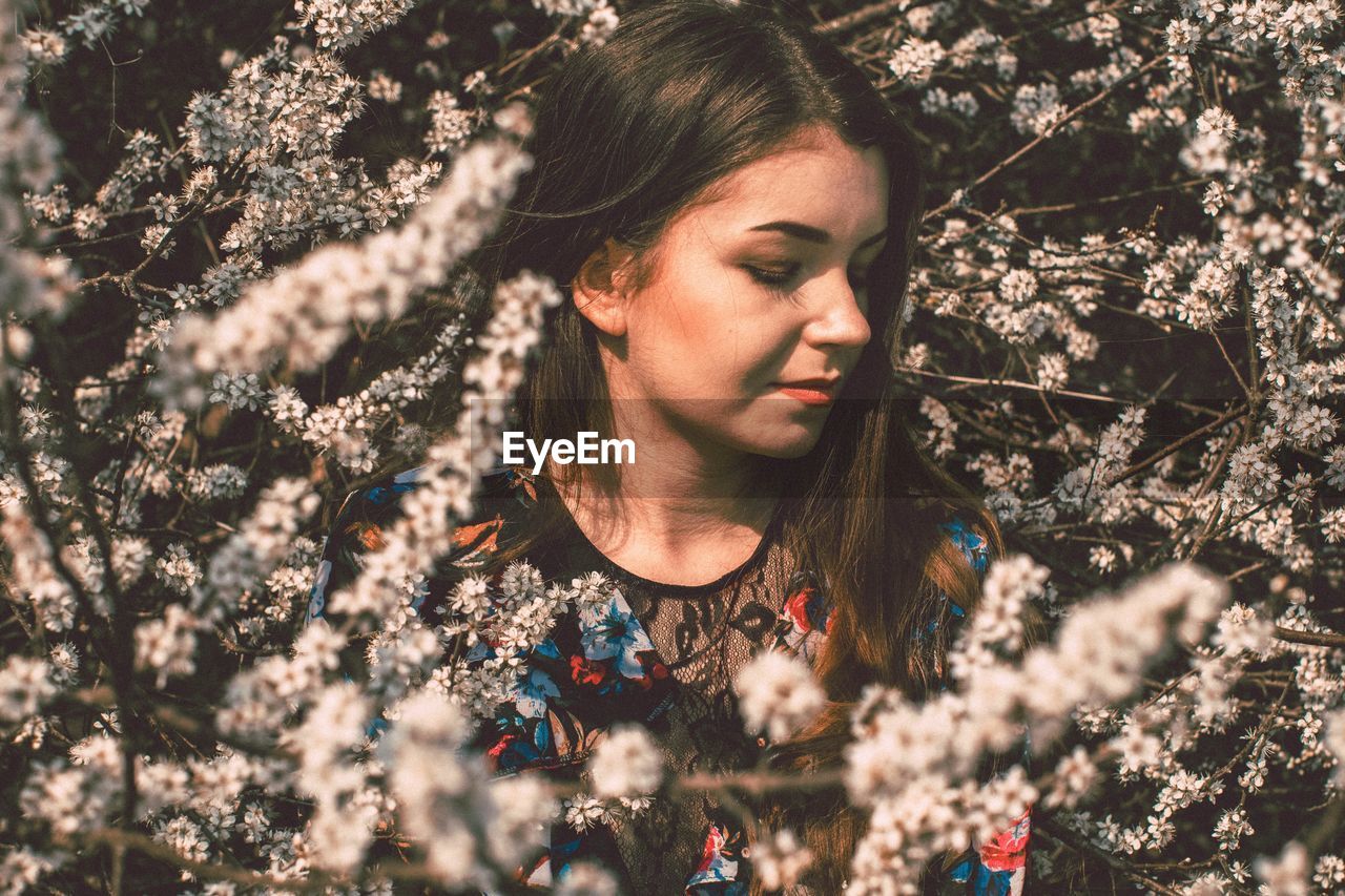 PORTRAIT OF YOUNG WOMAN WITH TREE IN BACKGROUND